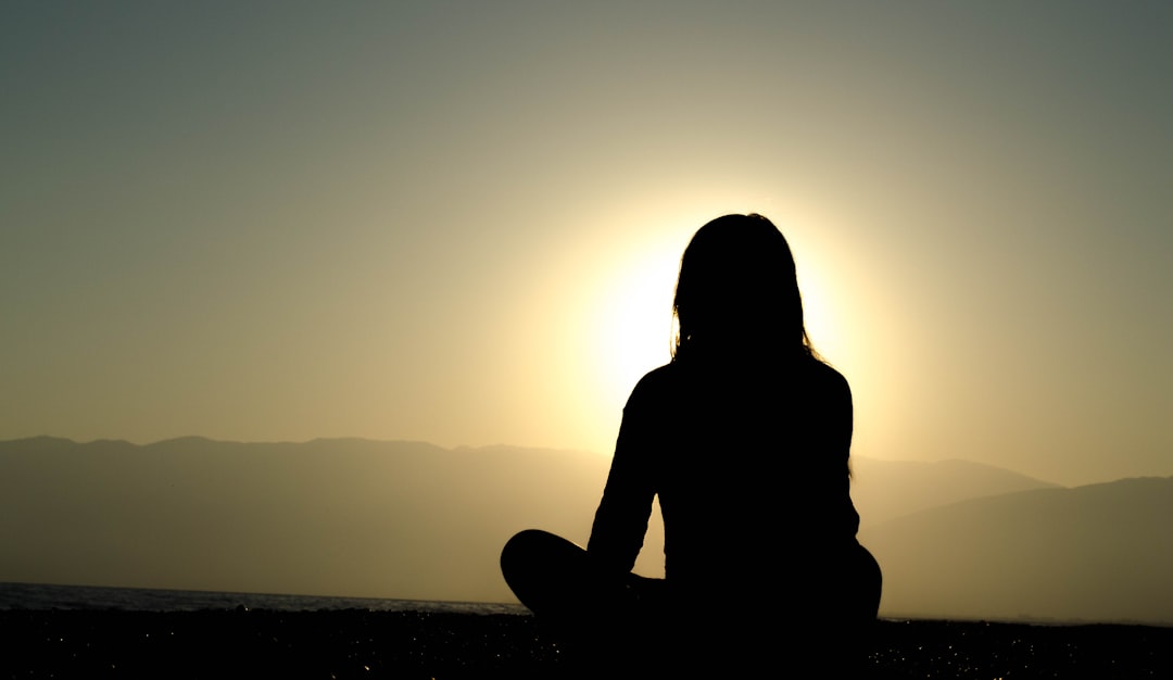 Photo by Dingzeyu Li on Unsplash silhouette of a women sitting on a mountain top watching a sunrise